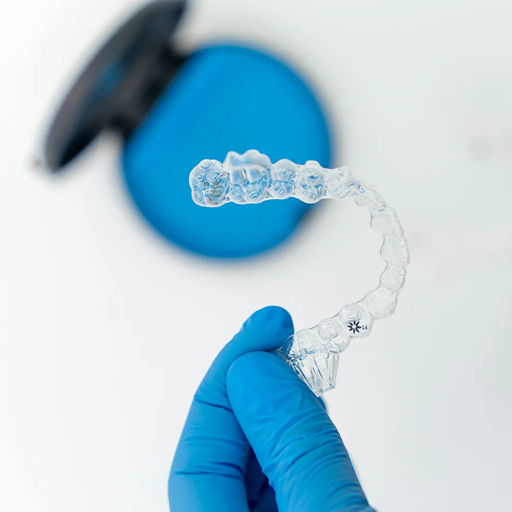 gloved hand holding a clear aligner tray