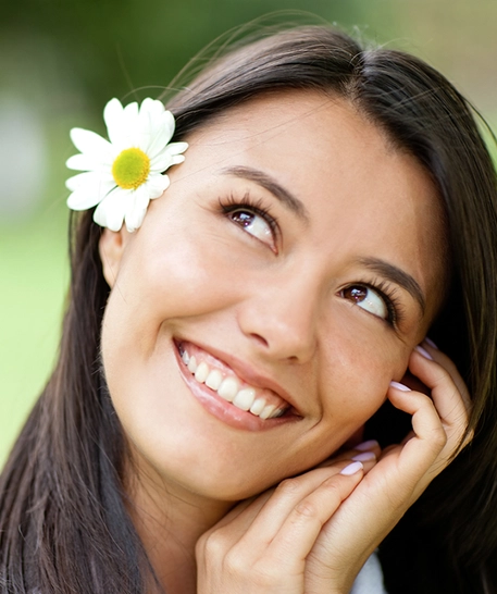 close up of young Hawaiian lady with flower in her hair smiling happily with straight white teeth